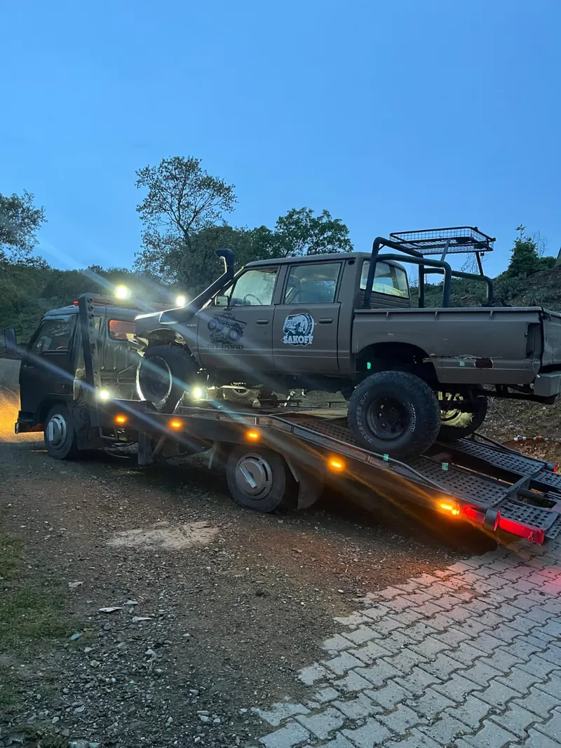 Salihli oto çekici — gece, amber ışıkları yanan kurtarıcıya yüklenen 4x4 pickup